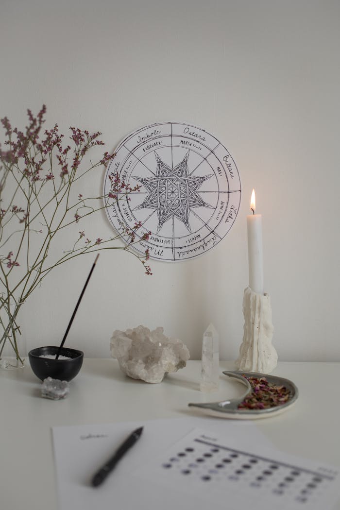 Cozy spiritual setting with candle, crystals, and astrology chart for peaceful meditation.